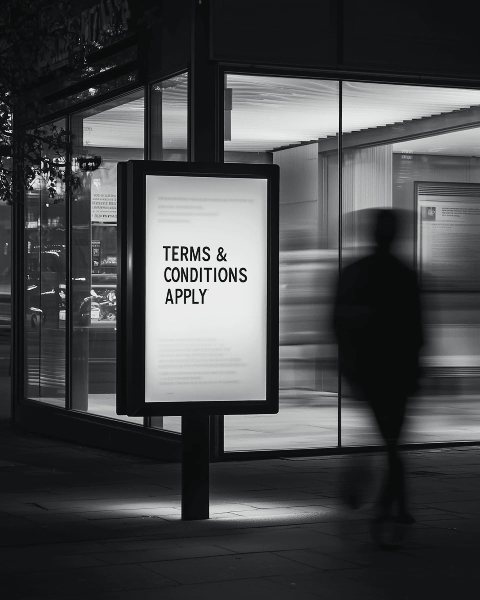 Illuminated street billboard reading Terms & Conditions Apply at night